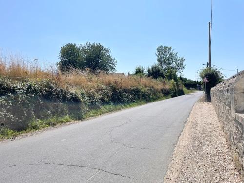 an empty road next to a stone wall at La clairiere Maison spacieuse rénovée joliment décorée tout confort 12 p 2 sdb 2 wc grand jardin clos, belle terrasse aménagée, parking privatif, ping pong baby foot proche Omaha Beach et Bayeux in Crouay
