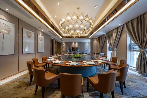 a dining room with a table and chairs and a chandelier at YTL OuYue International Hotel in Wenzhou