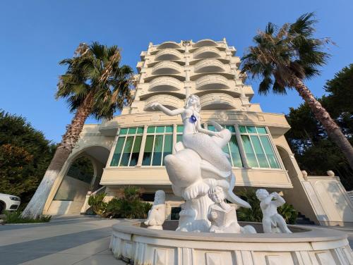 a statue in front of a building with palm trees at Hotel Vila Barbaut in Karpen