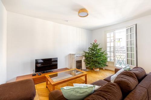 - un salon avec un canapé et un arbre de Noël dans l'établissement GuestReady - Confort familial avec balcon, à Paris