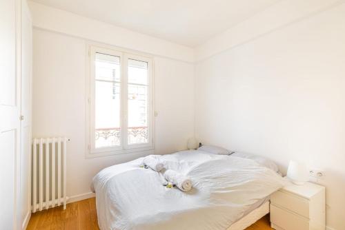 une chambre blanche avec un lit et une fenêtre dans l'établissement GuestReady - Confort familial avec balcon, à Paris
