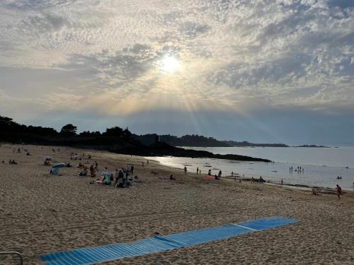 a group of people on a beach with the sun at Le 44 - Maison familiale - Grand confort - 700m Plages in Dinard
