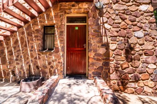 a brick building with a red door and a bench at ATKV Klein-Kariba in Bela-Bela