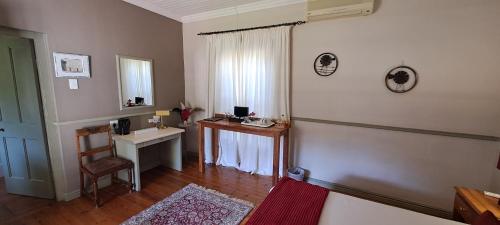 a room with a table and a desk and a mirror at HouseMartin Lodge & Self Catering in De Rust