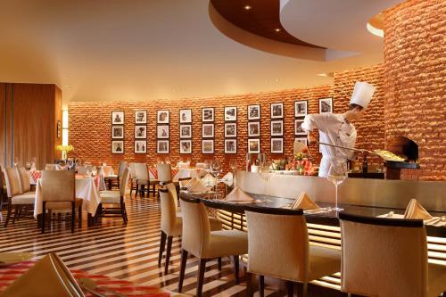 a restaurant with tables and a chef preparing food at Sheraton Ningbo Hotel - Tianyi Square in Ningbo
