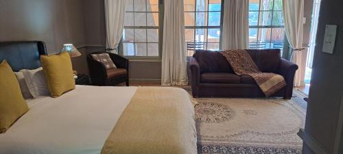 a bedroom with a bed and two chairs and a couch at HouseMartin Lodge & Self Catering in De Rust