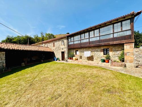 an old stone building with a grass field in front of it at Casona del Marquesado in Argüeso