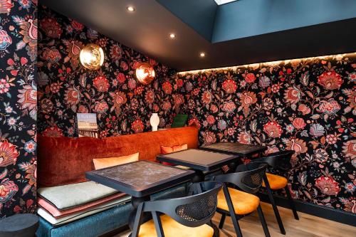 a restaurant with tables and chairs and floral wallpaper at Hôtel Hiro Paris in Paris