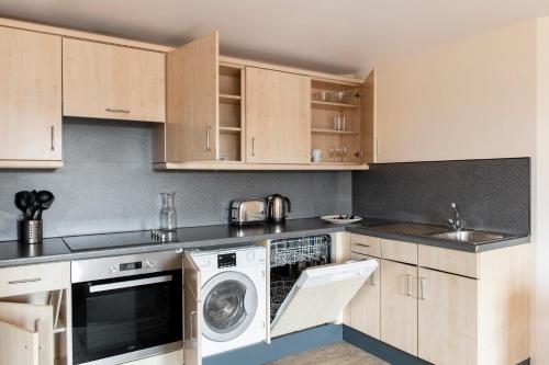 a kitchen with wooden cabinets and a washer and dryer at SACO Nottingham The Ropewalk in Nottingham