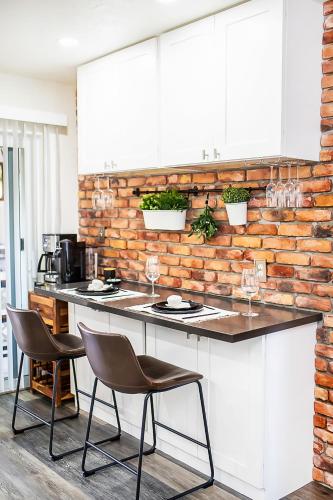 a kitchen with a counter and chairs and a brick wall at Brick Enclave with Mini Golf & SPA, 5mins to beach in Naples
