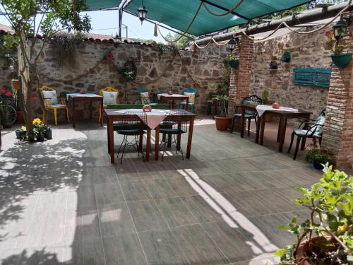 Un patio con mesas y sillas y un muro de piedra. en HAYAT ALTI OTEL ayvalık, en Ayvalık
