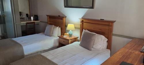 a hotel room with two beds and a chair at HouseMartin Lodge & Self Catering in De Rust
