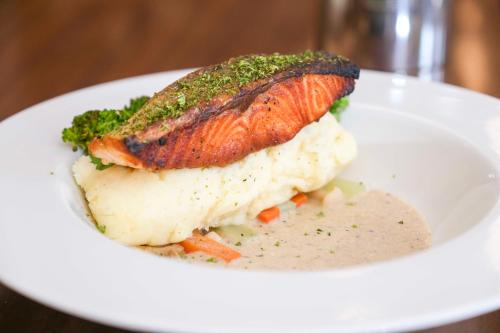 a white plate with a fish on top of mashed potatoes and broccoli at Best Western Plus The Ivywall Hotel - Palawan in Puerto Princesa City