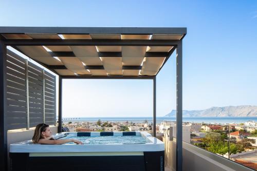 a woman laying in a hot tub on a balcony at Sapphire Blue Suites in Kissamos