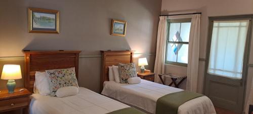 a bedroom with two beds and two windows at HouseMartin Lodge & Self Catering in De Rust