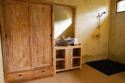 a bathroom with a sink and a wooden cabinet at Soka Villa in Ubud