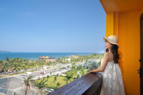 a woman standing on a balcony looking out at the ocean at Zenta Sea View Hotel in Da Nang