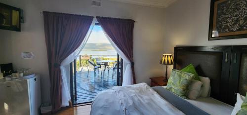a bedroom with a bed and a view of a balcony at Lagoon Lodge in Knysna