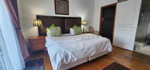 a bedroom with a bed with white sheets and green pillows at Lagoon Lodge in Knysna