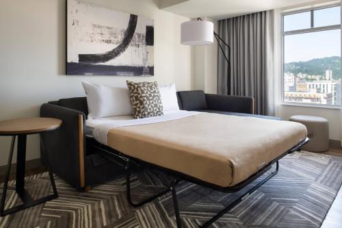 a bedroom with a bed and a table and a window at The Bidwell Marriott Portland in Portland
