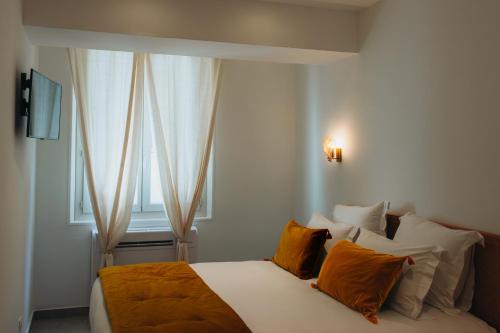 une chambre avec un lit avec des oreillers orange et une fenêtre dans l'établissement Prestigieux T4 à rue Sainte by Maison Galante, à Marseille