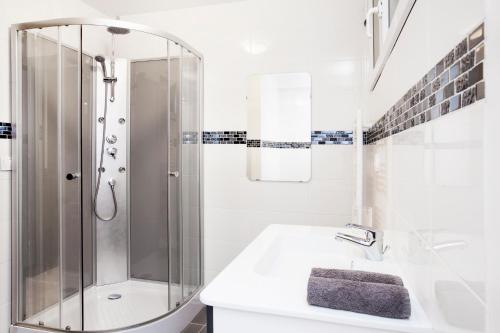 une salle de bain blanche avec une douche et un lavabo dans l'établissement Manray House - Beautiful Three Bedroom Apartment- Paris Center, à Paris