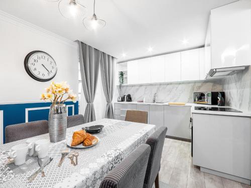 une cuisine et une salle à manger avec une table et une horloge dans l'établissement Manray House - Beautiful Three Bedroom Apartment- Paris Center, à Paris