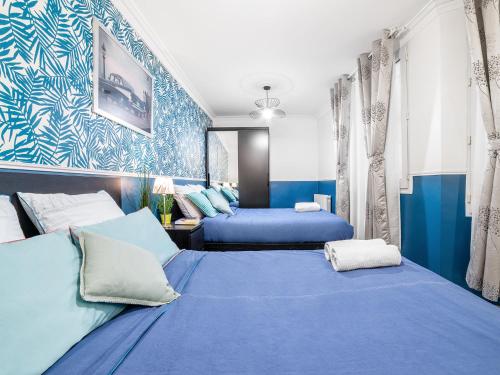 deux lits dans une chambre aux murs bleus dans l'établissement Manray House - Beautiful Three Bedroom Apartment- Paris Center, à Paris