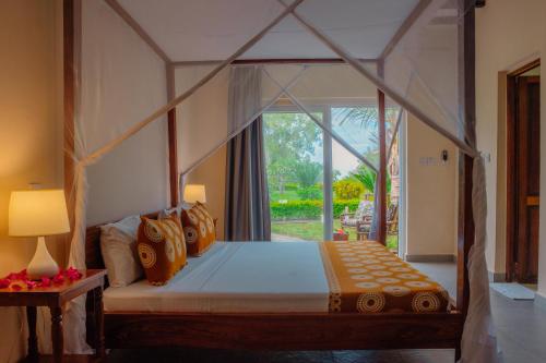 a bedroom with a canopy bed with a window at Filao Beach by Sansi in Uroa