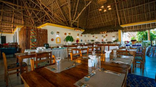 a restaurant with wooden tables and chairs in a room at Filao Beach by Sansi in Uroa