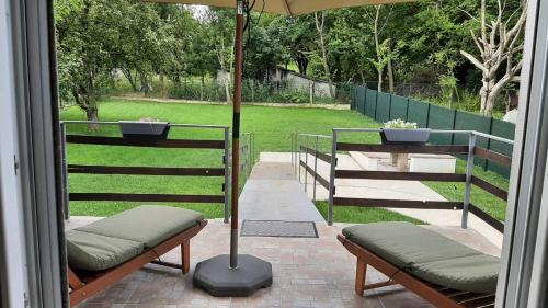 a porch with two benches and an umbrella at Green sanctuary 30 min from downtown Belgrade in Donja Ralja