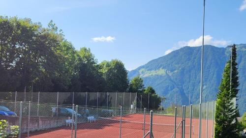 a tennis court with mountains in the background at SoloHike MountainView in Seelisberg