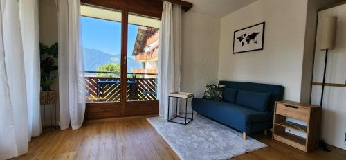 a living room with a blue couch and a large window at SoloHike MountainView in Seelisberg