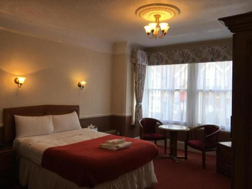 a hotel room with a bed and a table and a window at Grosvenor Hotel Rugby in Rugby
