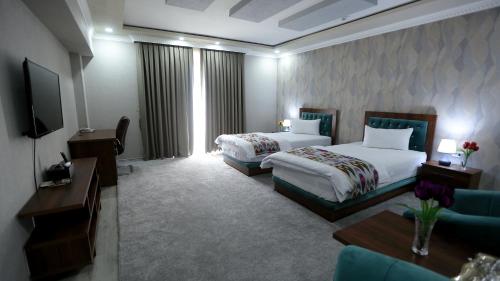 a hotel room with two beds and a television at Ахсикент отель in Namangan