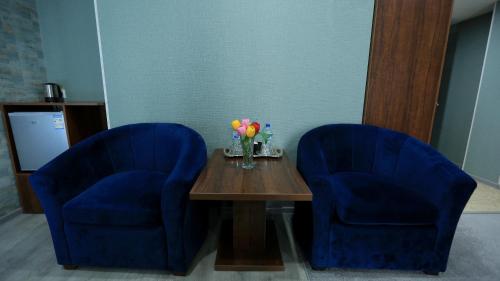 two blue chairs and a wooden table with flowers on it at Ахсикент отель in Namangan