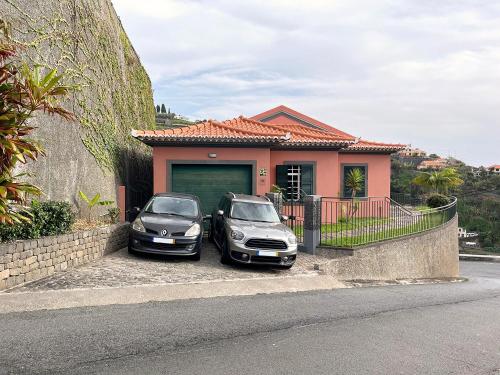 two cars parked in front of a house at Casa Coelho in Ponta do Sol
