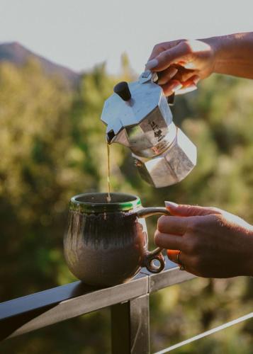 a person is pouring coffee into a cup at Award-winning A-frame Chalet W Cedar Tub & Views in Julian