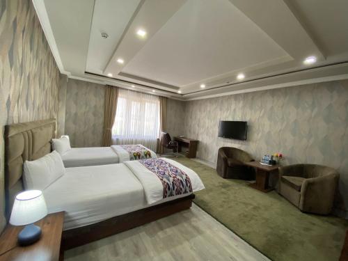 a hotel room with two beds and a television at Ахсикент отель in Namangan