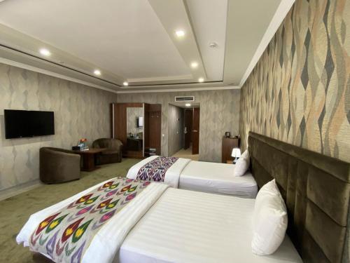 a hotel room with two beds and a flat screen tv at Ахсикент отель in Namangan