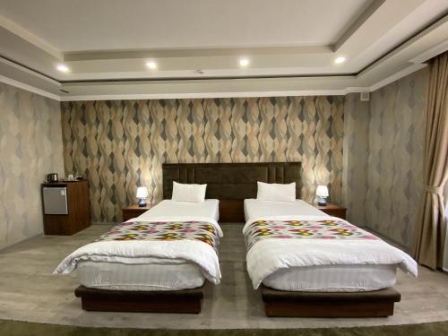 a bedroom with two beds and a wall at Ахсикент отель in Namangan