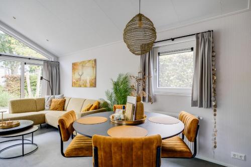 a living room with a couch and a table at Modern ingericht chalet op groen park op de Veluwe in Epe