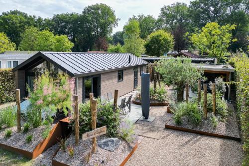 a garden in front of a small building at Modern ingericht chalet op groen park op de Veluwe in Epe