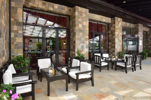 a patio with chairs and tables and windows at Snezhanka Hotel Pamporovo-All inclusive & Half Board in Pamporovo