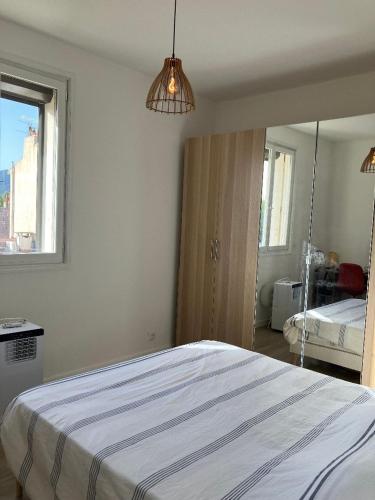une chambre blanche avec un lit et un miroir dans l'établissement T3 refait neuf au Centre du Mourillon à TOULON, à Toulon