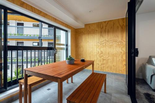 a room with a wooden table and a balcony at Stellar Central City Apartment - Hagley Park in Christchurch