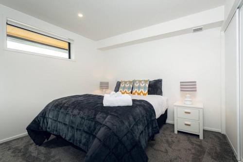 a white bedroom with a bed and a window at Stellar Central City Apartment - Hagley Park in Christchurch