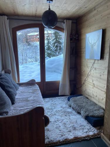 - une chambre avec un lit et une fenêtre avec de la neige à l'extérieur dans l'établissement Wintergarten, à Valmorel