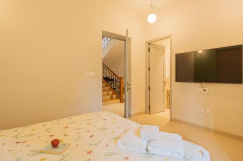 a bedroom with a bed and a flat screen tv at ELIVAAS 4 BHK with Pvt Pool near Baga - Celest in Old Goa
