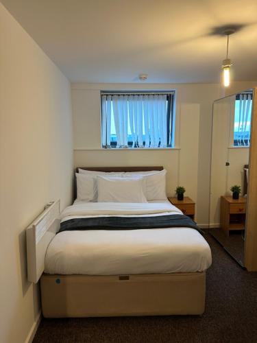 ein Schlafzimmer mit einem Bett mit weißen Kissen und einem Fenster in der Unterkunft City Centre 2 Bed Room 2 Bath Room Apartment with En-suite in Liverpool